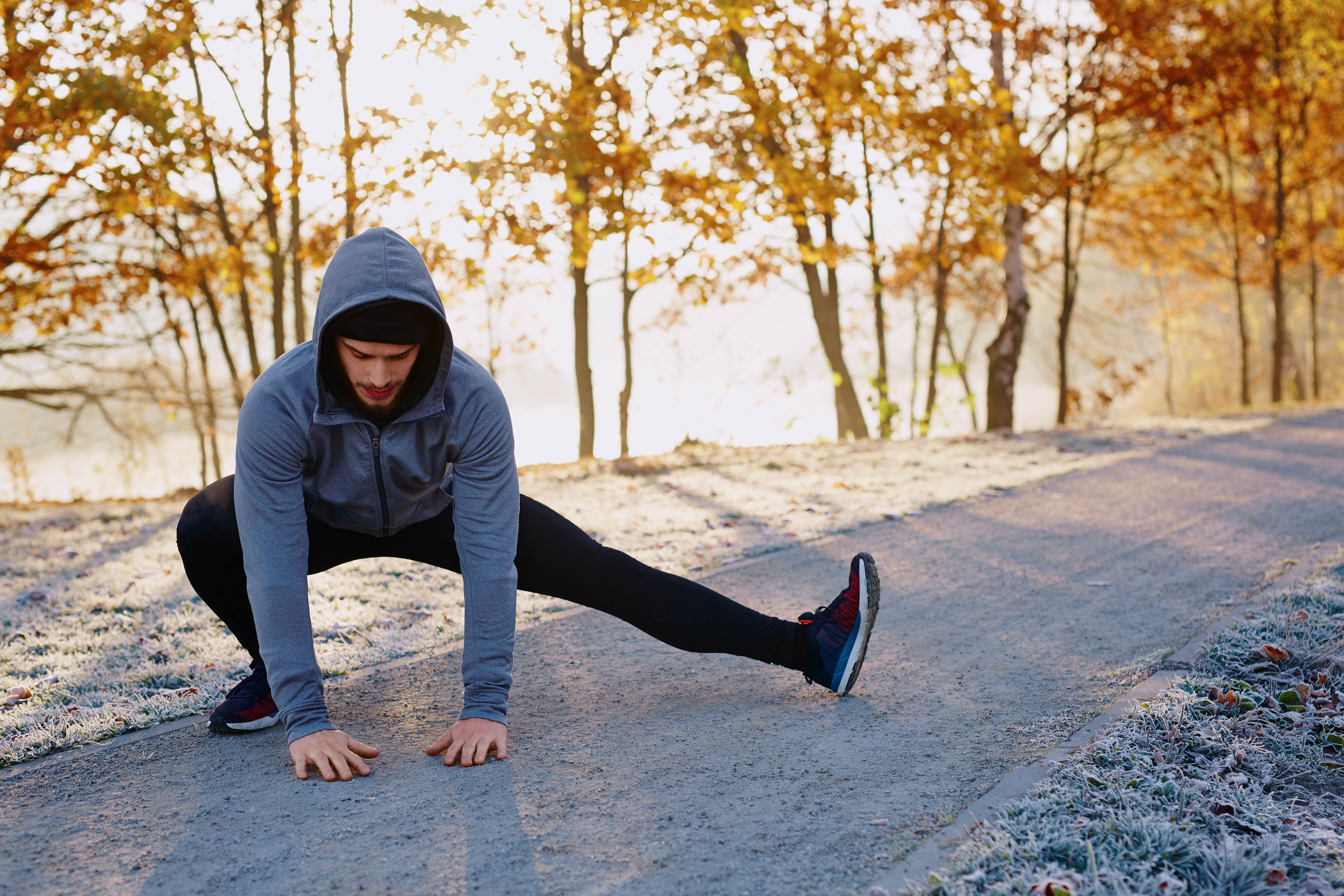 Young fit man stretching on the ground in the winter before going for a run